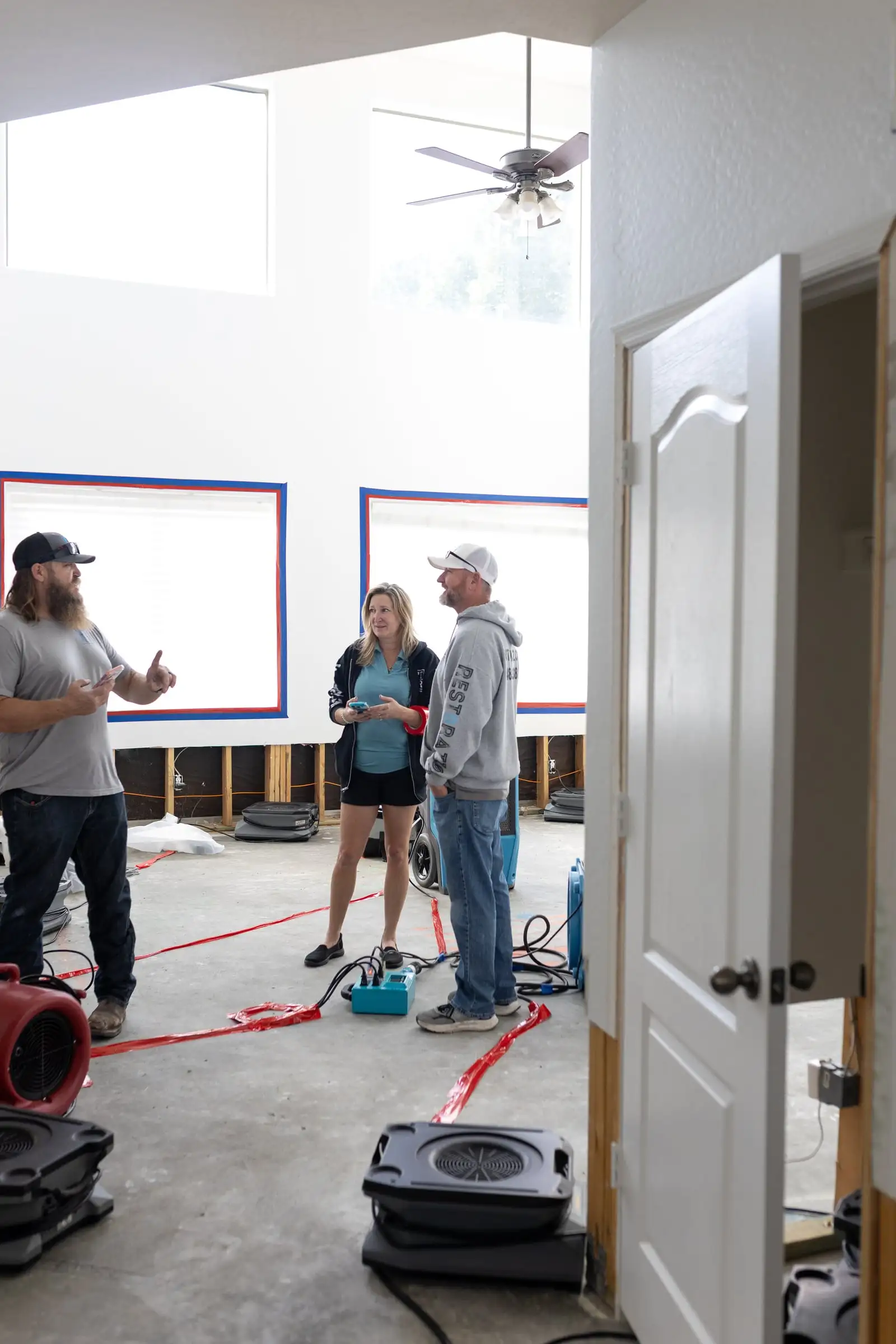 Fast Track team members talking through the drying plan in a home with flood-cut walls and air movers running