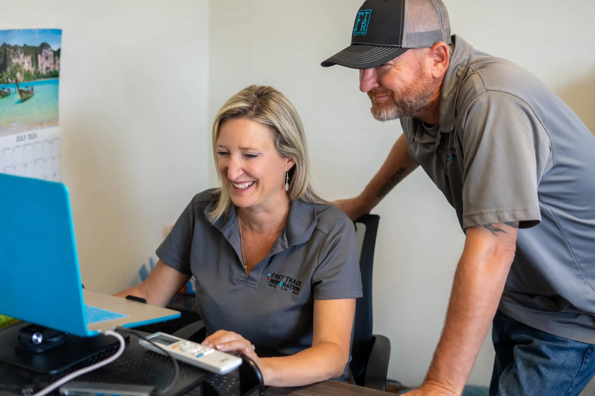 Becci Stoflet and Brian Bradford reviewing job documentation on a laptop at the Fast Track office
