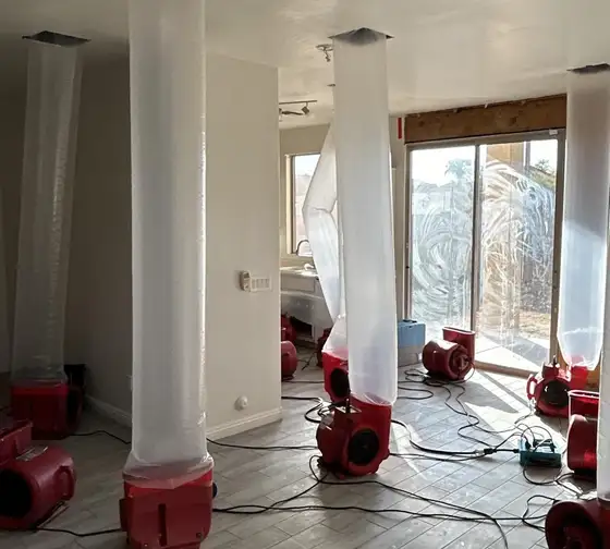 Air movers blowing through ducting tubes to dry the ceiling of a water-damaged home