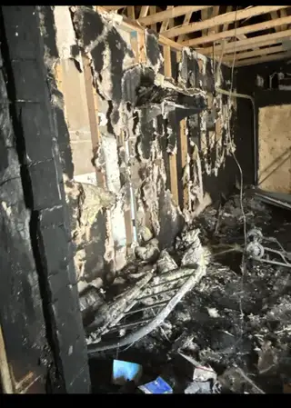 Charred wall framing and burned debris inside a fire-damaged house