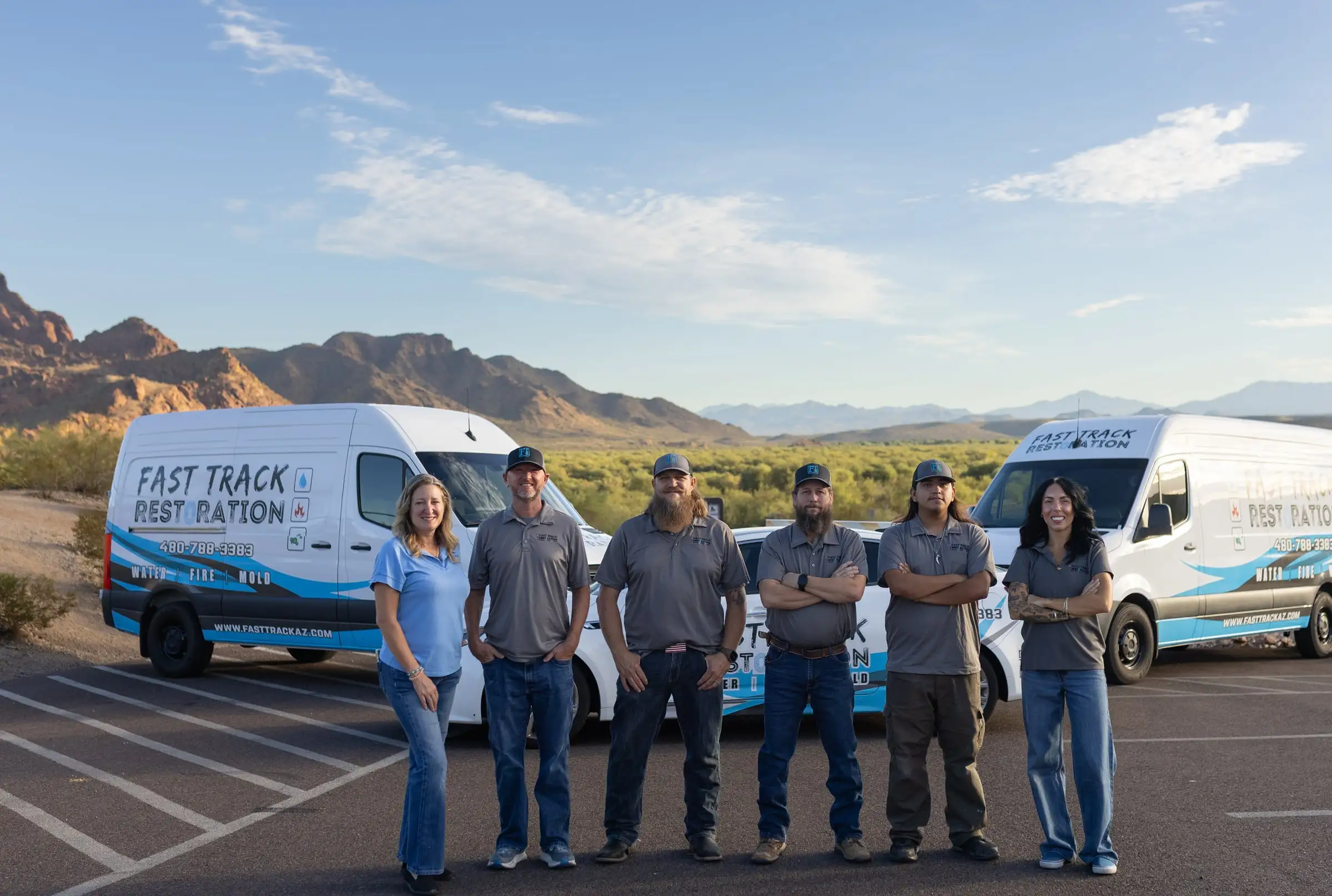 The Fast Track Restoration team standing in front of their company vans in the Arizona desert